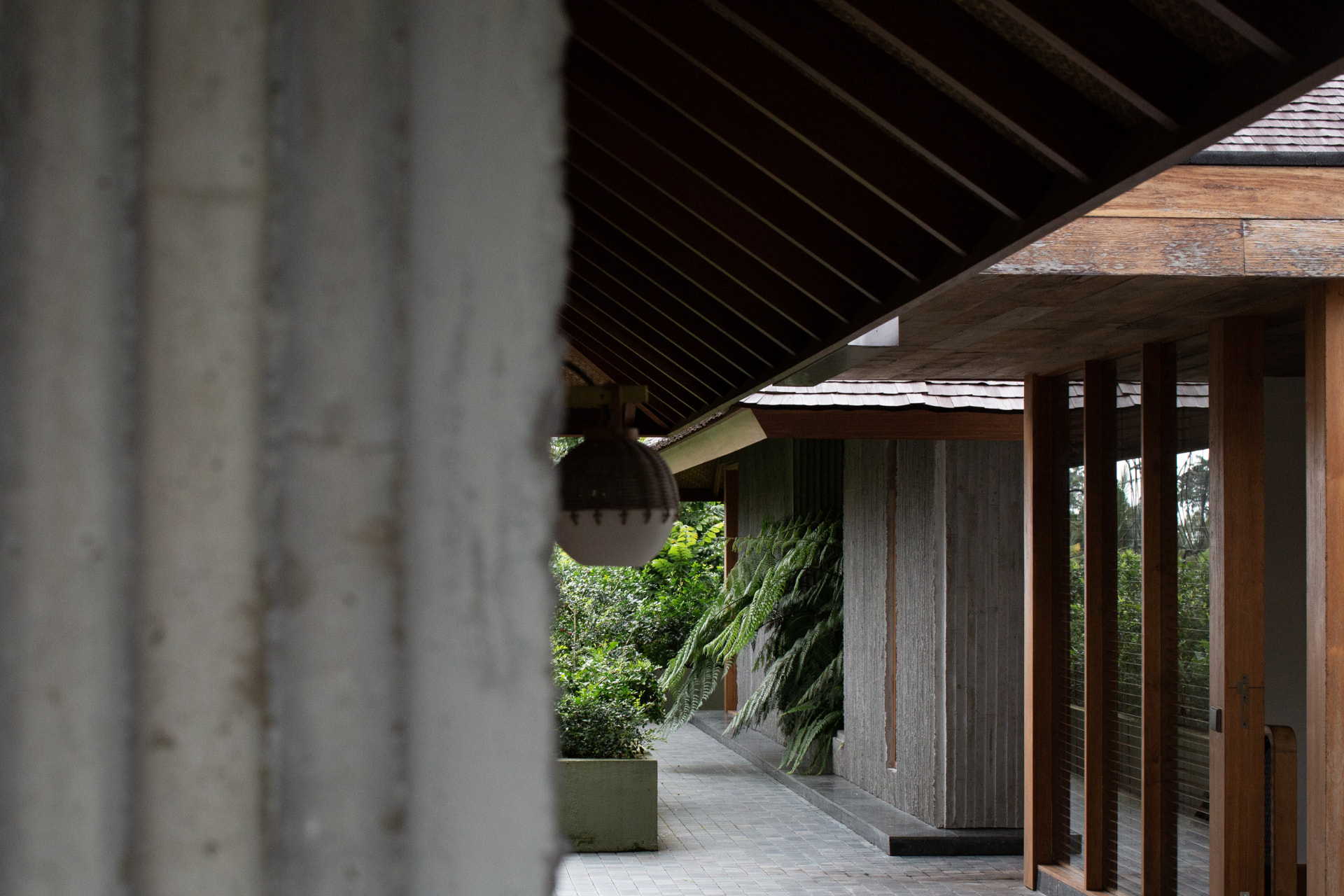 Timber-lined corridor and master bedroom pavilion surrounded by tropical planting